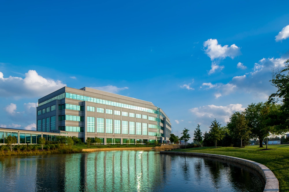 a pond in the foreground with a multi-story office building in the background